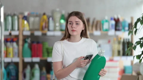 Girl buyer scans qr code on liquid powder label Stock Footage 313099247