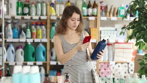 Girl buyer scans qr code on tile cleaner spay label Stock Footage 320923188