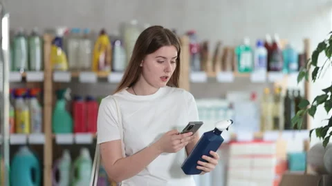 Girl buyer scans qr code on tile cleaner spray label Stock Footage 322119461