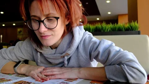 The girl in the cafe at the big window looking at the menu Light skin. glasses o 動画素材 129068962