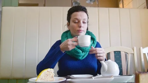 Girl in the cafe drinking tea, she sits at the table and looks out the window Stock-Footage 73003135