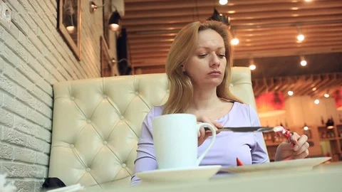 A girl in a cafe eats cheese pancakes with sour cream jam and fresh berries with Stock Footage 74627170