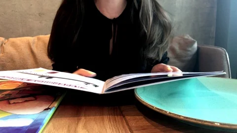 Girl in a cafe leafs through the restaurant menu Stock Footage 116559992