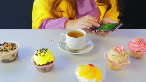 The girl in a cafe at the table with cakes leafing through the news in the 库存影片 110807969