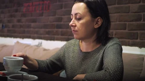 A girl in a cafe at a table drinking tea. cute brunette at the table Stock Footage 170783610