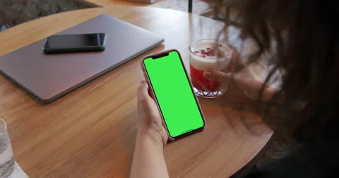 Girl in the cafe using an iPhone Xs Max with a green screen. Stock Footage 135814766