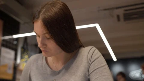Girl in a cafe, write with a pen in a notebook and thoughtfully check the task Stock Footage 126951456