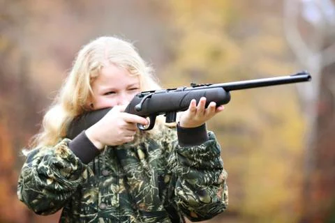 Girl in camouflage aiming rifle in forest Stock Photos