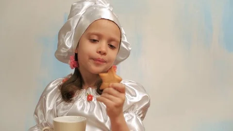 Girl in cap chef dunks cookie in milk. Showing thumb up Stock Footage 73874079