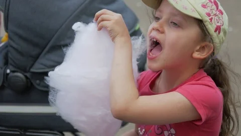 Girl in cap eats cotton candy, closeup. Video stock 75245886