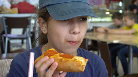 Girl in a cap eats pizza in a cafe 4K Stock Footage 112682851