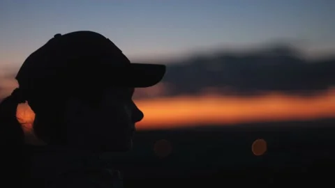 A girl in a cap with a pigtail on the background of sunset Stock Footage 220714718