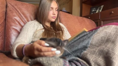 Girl with cat reading a book Stock Footage 292845686
