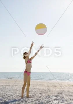 Girl Catching Beach Ball On Beach
