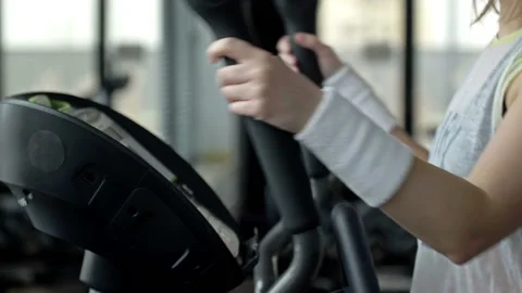 Girl changed the load mode on the cardio machine and continues the exercise. Stock Footage 233283370