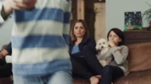 Girl changing channels while watching tv with family in living room Stock Footage 63861365