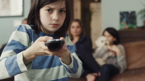 Girl changing channels while watching tv with family in living room Stock Footage 63861374