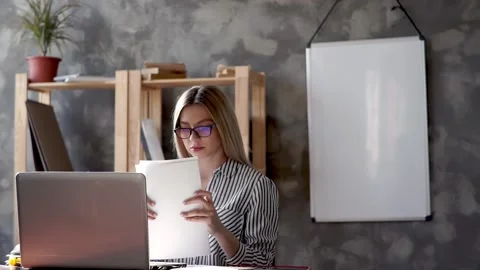 Girl checks a stack of documents sitting at a laptop .businesswoman holding Stock Footage 131525168