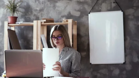 Girl checks a stack of documents sitting at a laptop .businesswoman holding Stock Footage 132585155