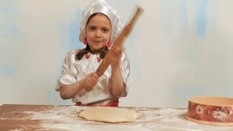 Girl chef with rolling pin knocking on palm and kneads the dough on table. Video stock 74183673