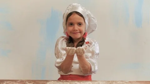 Girl chef without teeth blows to handful flour. Looking at camera and laughs. Stock Footage 74170955