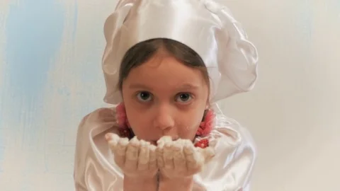 Girl chef without teeth blows to handful flour. Looking at camera and laughs. Stock Footage 84281287