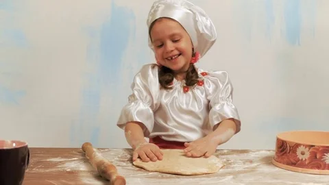 Girl chef without a tooth laughs and smoothes the dough on the table. Stock Footage 74183594
