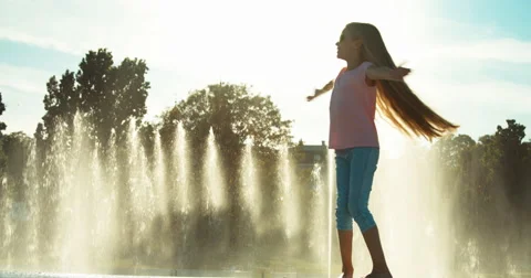 Girl child 7-8 years in sunglasses spinning on fountain background Stock Footage