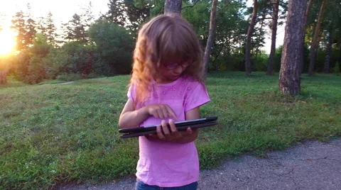 Girl child in glasses enthusiastically working on a tablet computer. Stock Footage