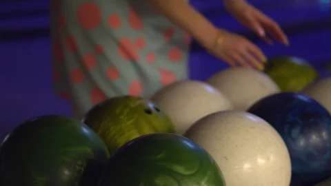 A girl chooses a ball before throwing while playing bowling in a bowling club Stock Footage 113643690