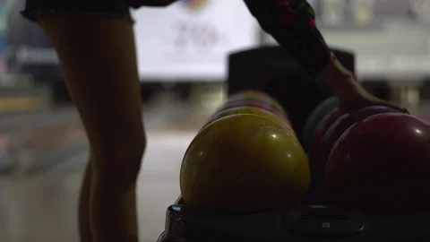 A girl chooses a ball before throwing while playing bowling in a bowling club Stock Footage 120467826