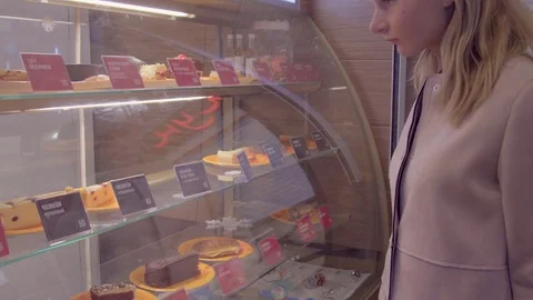 The girl chooses a cake at the window Stock Footage 73364099