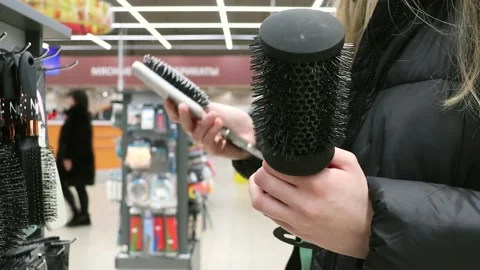 Girl chooses combs in the store. Combs in hand Stock Footage 231910074
