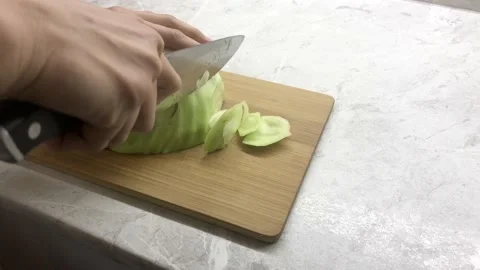 Girl chops a green head of cabbage with a knife on a board. Stock Footage 140204200