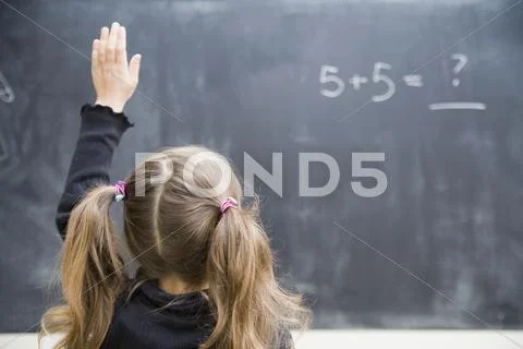 Girl in classroom with raised hand Stock Photos