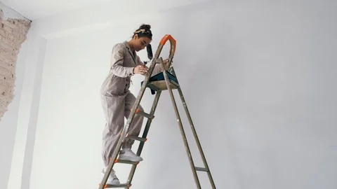 Girl climbing down a ladder while holding a paint roller Stock Footage 112106040