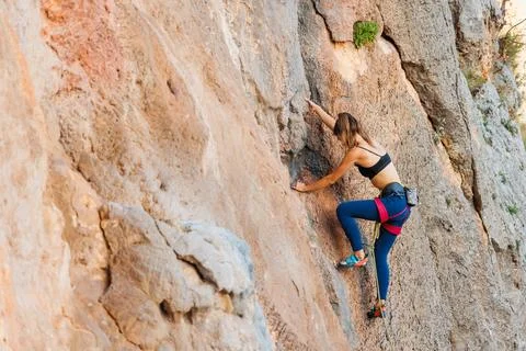 The girl climbs the rock. The climber is training to climb the rock. A strong Stock Photos
