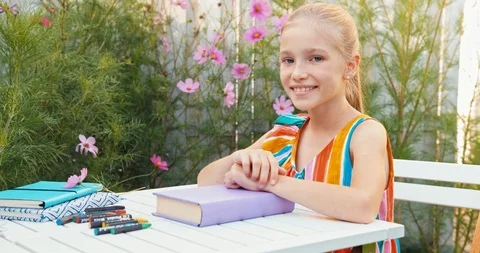 Girl closing the book at the table outdoors Stock Footage