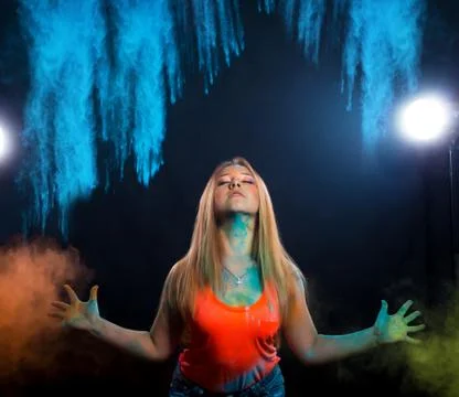 Girl with colored powder exploding around her and into the background. Stock Photos