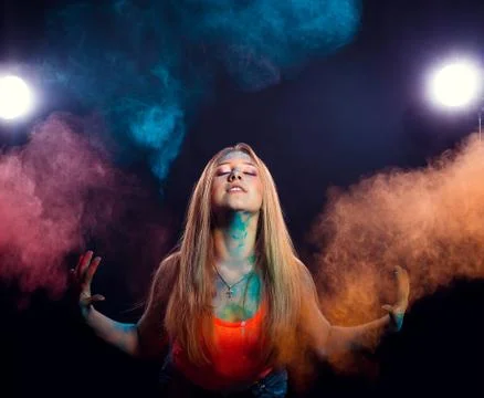 Girl with colored powder exploding around her and into the background. Stock Photos