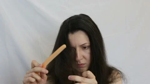 The girl combs tangled split ends of hair with a comb. The average shot, inside, Stock Footage 92518281