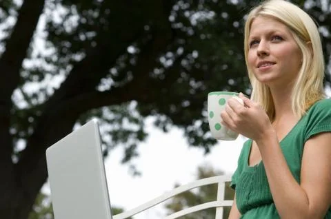 Girl on computer with mug Stock Photos