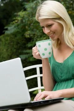 Girl on computer with mug Stock Photos
