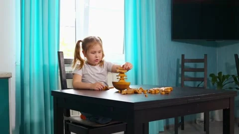 Girl is constructing patterns with wooden blocks at a table in a learning room Stock Footage 333517900