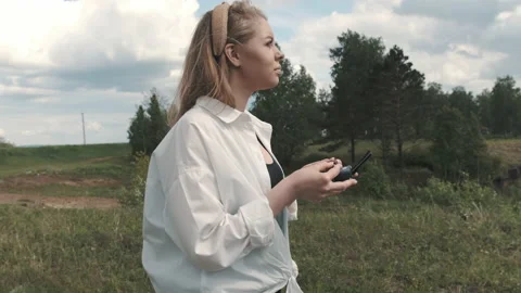 Girl with a control panel over a drone stands in a field Stock Footage 131202485