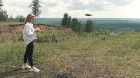 Girl with a control panel over a drone stands in a field Stockbeeldmateriaal 131202902