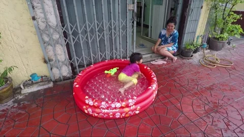 The girl cools in the inflatable water pool on the street, Bangkok, Thailand Stock Footage 158503673