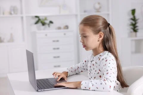 Girl with correct posture using laptop at white desk indoors Stock Photos