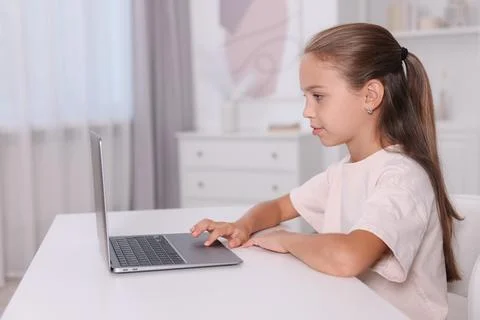 Girl with correct posture using laptop at white desk indoors Stock Photos