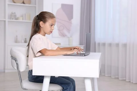 Girl with correct posture using laptop at white desk indoors Stock Photos